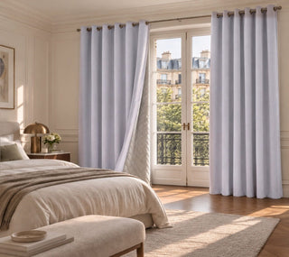 Rideau occultant violet lavande à œillets devant une porte-fenêtre de chambre, un panneau ouvert laisse voir la doublure matelassée