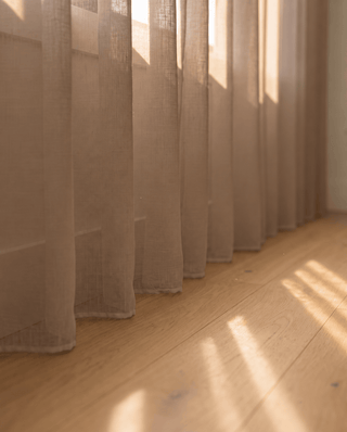 Bas du voilage camel sur parquet, rayons de soleil